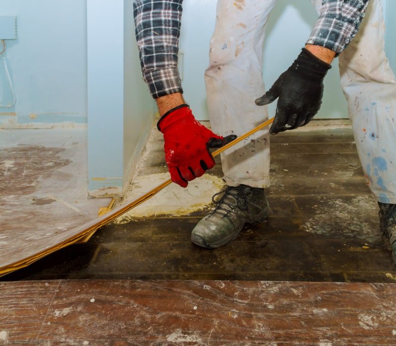 Handyman during work of removing oldlaminated parquet flooring home renovation