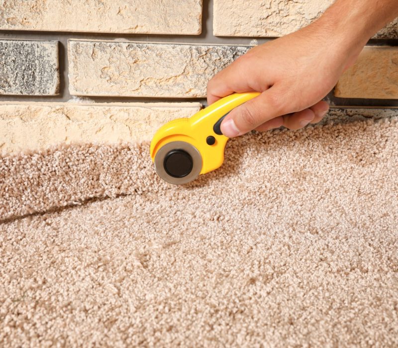 Man cutting new carpet flooring indoors, closeup